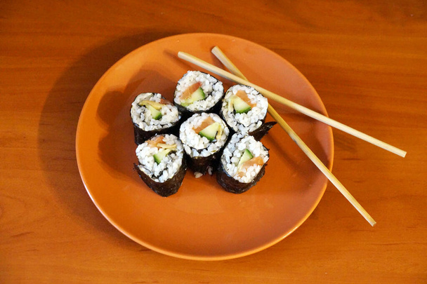 Sushi japonés y palos de madera en un plato. - Foto, Imagen