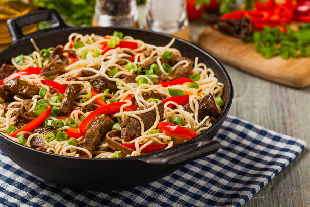 Chinese pasta with beef. Prepared in wok. Wooden background. Front view. - Foto, Imagen