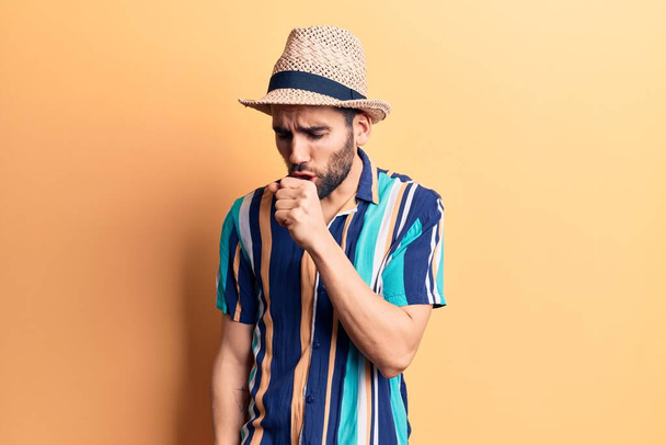 Young handsome man with beard wearing summer hat and shirt feeling unwell and coughing as symptom for cold or bronchitis. health care concept.  - Photo, Image