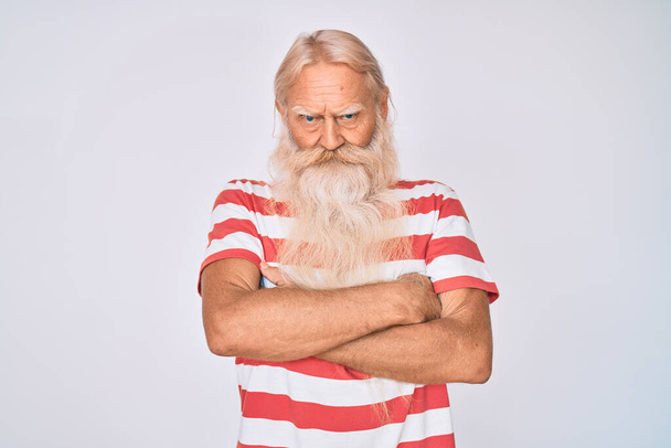Old senior man with grey hair and long beard wearing striped tshirt skeptic and nervous, disapproving expression on face with crossed arms. negative person.  - Photo, Image