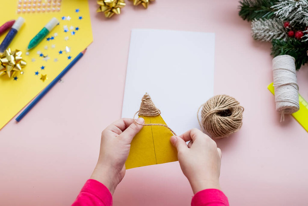 Concepto bricolaje. Cómo hacer la tarjeta de Navidad. Idea de Año Nuevo para niños. Instrucciones fotográficas paso a paso. Decora la tarjeta con el árbol de navidad.Creatividad de los niños. El chico hace una tarjeta de felicitación. Etapa 4 - Foto, imagen