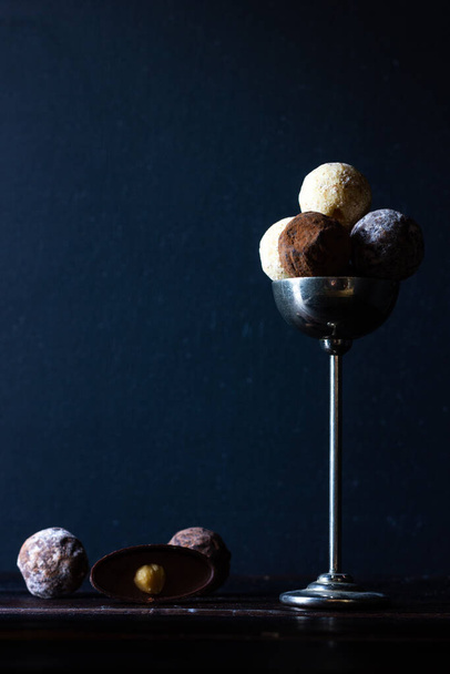 Chocolate truffles in a small vase on a wooden background in dark colors. Rustic style. Chocolate candies - 写真・画像