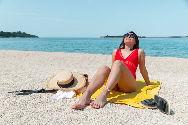 Seksikkäitä naisia punaisessa uimapuvussa aurinkoisella rannalla. kopioi tila - Valokuva, kuva