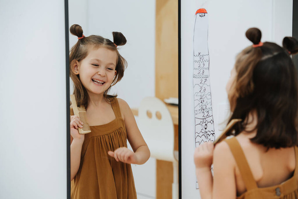 Chica cuida de su pelo y se ríe delante del espejo - Foto, imagen