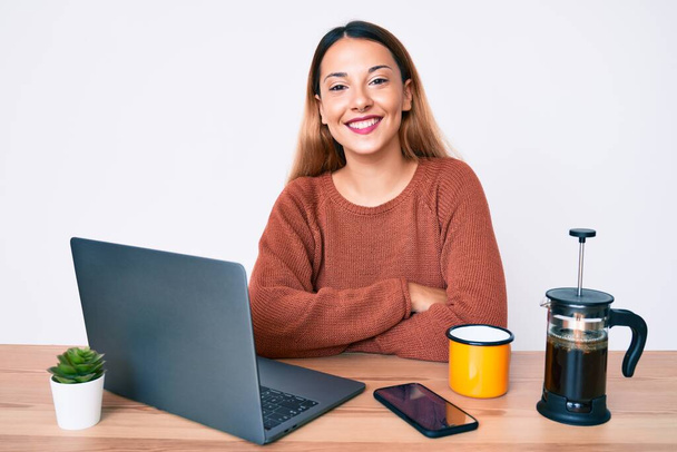 Fiatal barna nő dolgozik az irodában iszik egy csésze kávét boldog arc mosolyog keresztbe tett karokkal nézi a kamerát. pozitív személy.  - Fotó, kép
