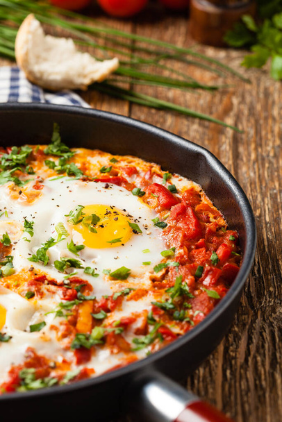 Shakshouka, schotel eieren gepocheerd in een saus van tomaten, chili pepers, uien. Vooraanzicht.  - Foto, afbeelding