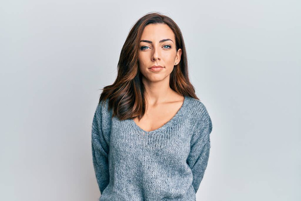 Jonge brunette vrouw draagt casual winter trui ontspannen met serieuze uitdrukking op het gezicht. eenvoudig en natuurlijk kijkend naar de camera.  - Foto, afbeelding