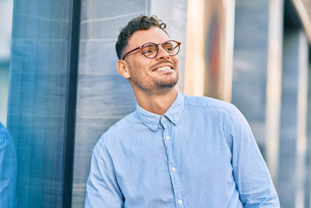Joven empresario hispano sonriendo feliz de pie en la ciudad. - Foto, imagen