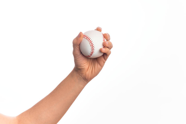 Mano di giovane caucasico che tiene palla da baseball su sfondo bianco isolato - Foto, immagini