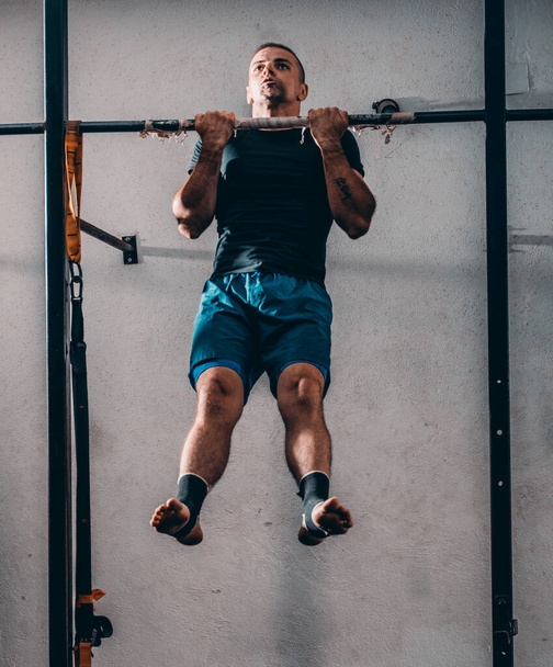 Young attractive caucasian crossfit sportsman working out in park, exercising on chin-up bar, doing pull-ups for arms and back muscles - Foto, immagini