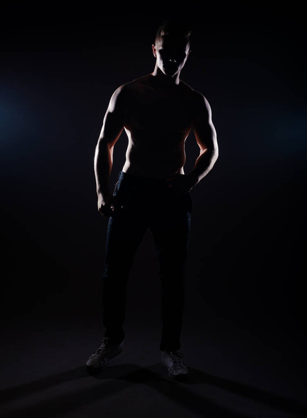 Trendy modern young man dressed posing shirtless in dark studio - Photo, Image