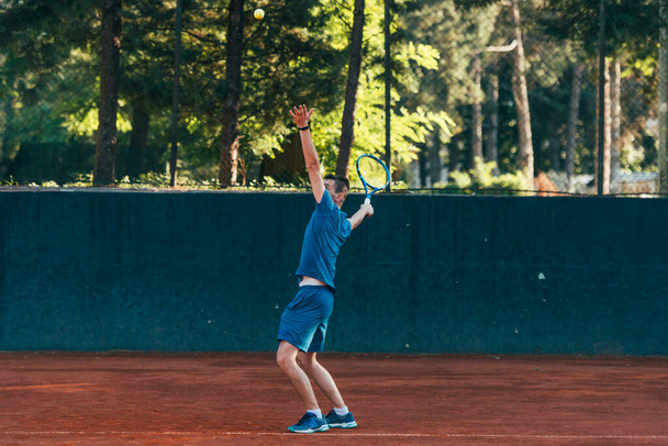 Profesyonel bir tenisçi kil tenis kortunda top servis ediyor. - Fotoğraf, Görsel