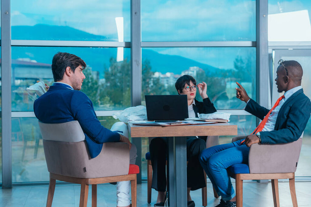 Wieloetniczni przedsiębiorcy dyskutują przy stole konferencyjnym w biurze - Zdjęcie, obraz