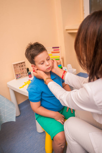 Female Pediatrician check's the throat and mouth of a young cute boy. - Fotó, kép