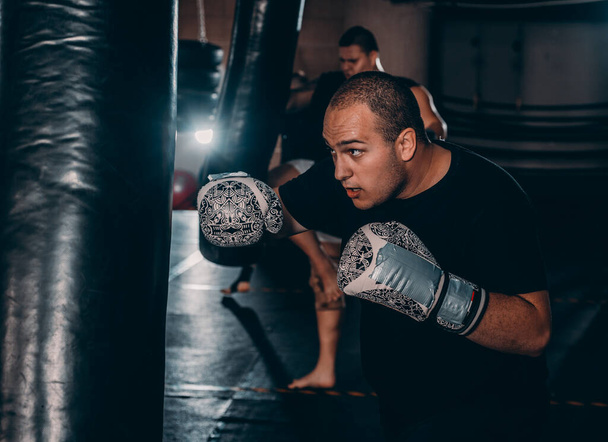 Az izmos harcos bokszzsákos ütéseket gyakorol. Az egészséges életmód koncepciója - Fotó, kép