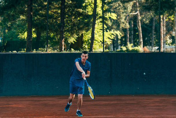A professional tennis player is serving ball on a clay tennis court - Foto, imagen