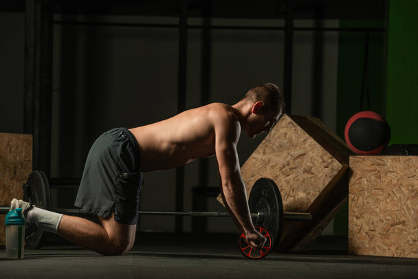 Athlète professionnel torse nu faisant l'entraînement d'abdos de torsion russe. Photo rapprochée d'un athlète masculin en forme faisant de l'entraînement en salle. - Photo, image