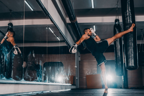 Вид на повну довжину тренувань з м'язового молодого боксера з мішком для ударів
 - Фото, зображення