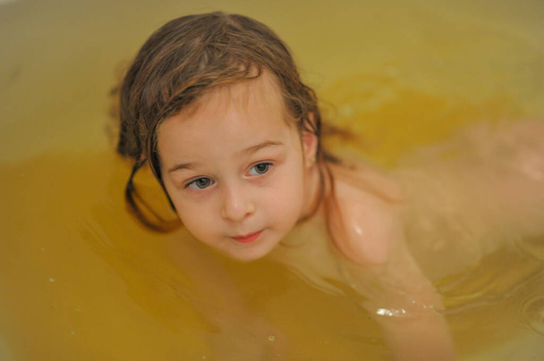Küçük tatlı bebek banyoda. Küçük kız beyaz bir küvette banyo yapıyor. Çocukluk temizliği, banyo. - Fotoğraf, Görsel