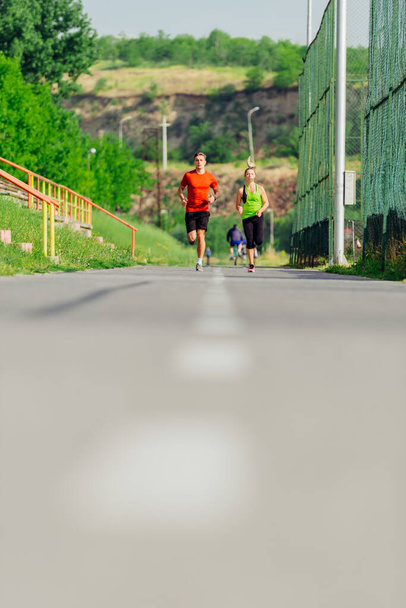 Молодые спортсмены и спортсменки бегают и бегают по дороге в парке - Фото, изображение