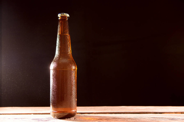 Bottle of beer on wooden table on a black background - Photo, Image