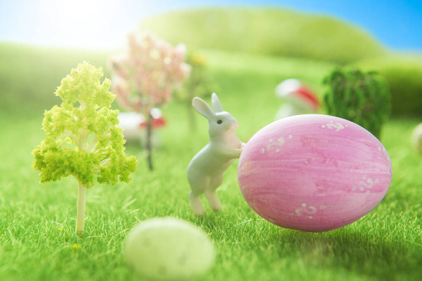 Rabbits near an easter eggs on a green grass field. - 写真・画像