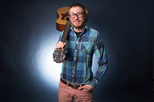 Hipster man with guitar on dark blue background. - Φωτογραφία, εικόνα