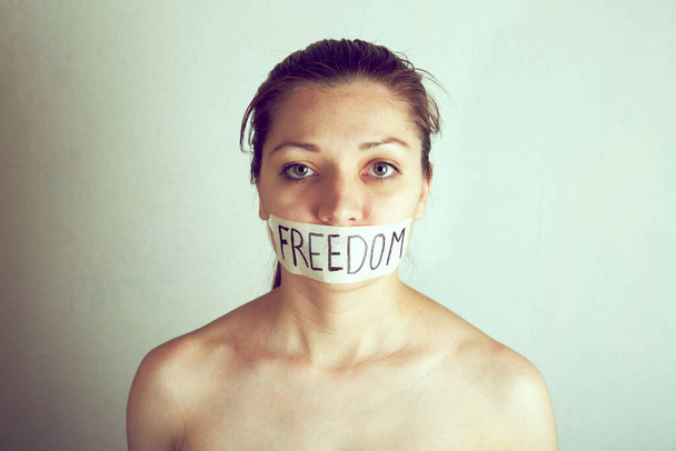 Woman with taped mouth with inscription word - freedom. - Φωτογραφία, εικόνα