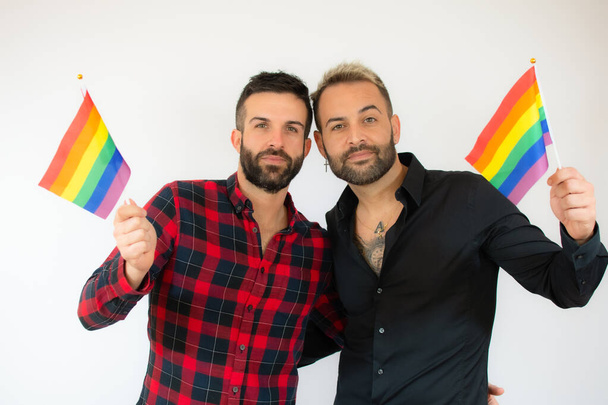 Счастливая пара геев с гомосексуальным флагом на белом фоне. - Фото, изображение