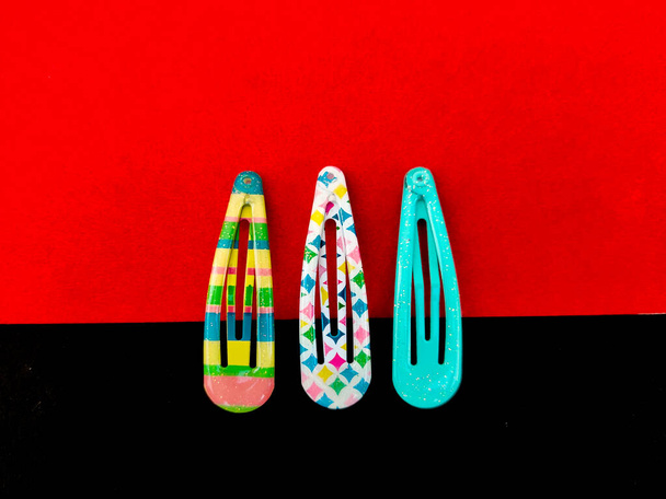 Tres patrones coloridos de clips para el cabello aislados sobre fondo rojo y negro - Foto, Imagen