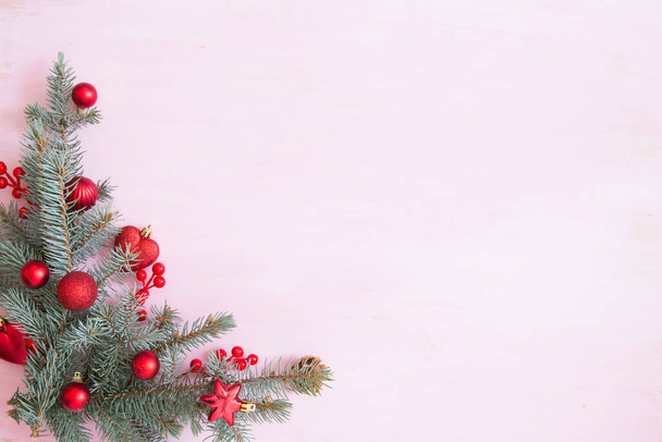 Pink wooden christmas background with fir-tree branch and red christmas decorations in the corner. Frame. View from above - Valokuva, kuva