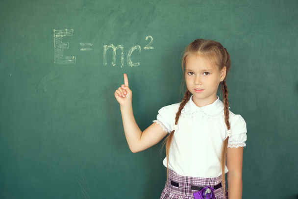 Portrait of caucasian happy child girl. School chalkboard or blackboard background. Free text copy space. Education and school concept. - Фото, изображение