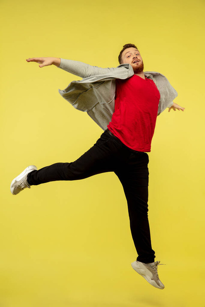 Full length portrait of young successfull high jumping man gesturing isolated on yellow studio background - Foto, Bild