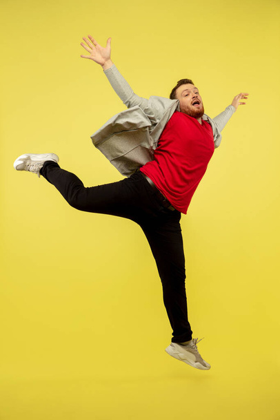 Full length portrait of young successfull high jumping man gesturing isolated on yellow studio background - Zdjęcie, obraz