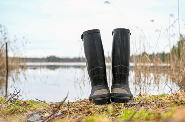 a pair of wellingtons standing infront of a lake - 写真・画像