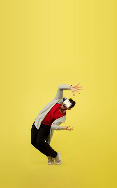 Full length portrait of young successfull high jumping man gesturing isolated on yellow studio background - Фото, изображение