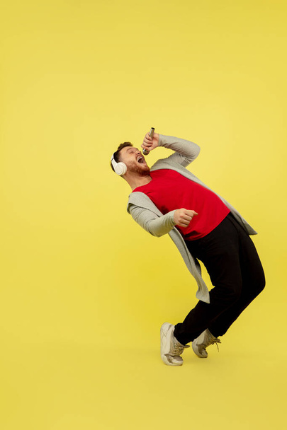 Full length portrait of young successfull high jumping man gesturing isolated on yellow studio background - Foto, Imagem