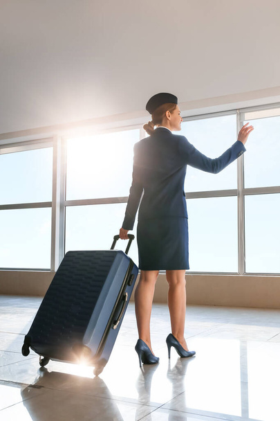 Młoda stewardessa z bagażem na lotnisku - Zdjęcie, obraz