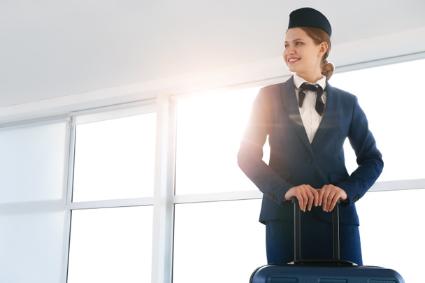 Молодая стюардесса с багажом в аэропорту - Фото, изображение