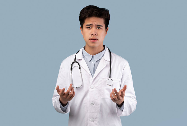 asiatico ragazzo in medico cappotto parlando con fotocamera gesturing - Foto, immagini