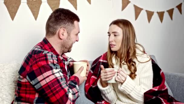 een man in een rood shirt en een vrouw in een witte trui die met elkaar praten over een kop cacao - Video
