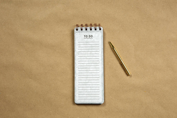 Top View of blank Notepad with empty To Do list on brown paper background, copy space or space for text, modern design with gold pen - Foto, Bild