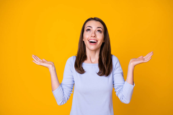 Photo of attractive pretty cheerful lady good mood open mouth excited overjoyed look up empty space sky catch arms rain drops wear casual shirt isolated vibrant yellow color background - Foto, Imagen