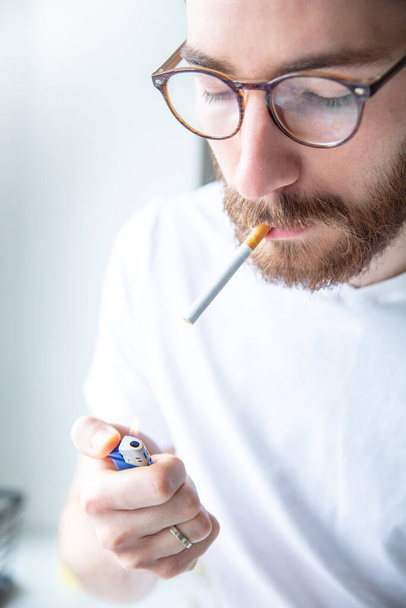 Smoking habit. Young adult man lighting a cigarette. - Fotó, kép