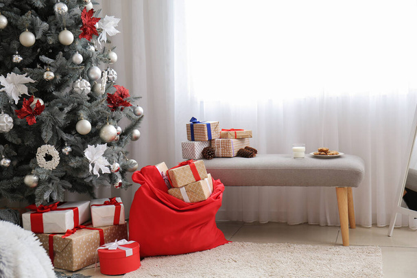 Wnętrze nowoczesnego pokoju z torbą Santa, smakołyki i choinki - Zdjęcie, obraz