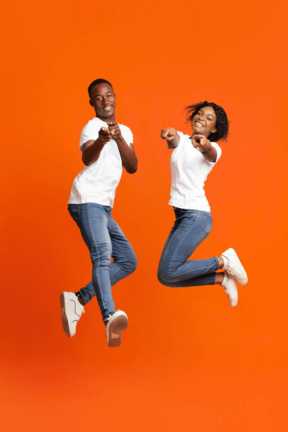 Счастливые чернокожие влюбленные позируют на фоне оранжевой студии - Фото, изображение