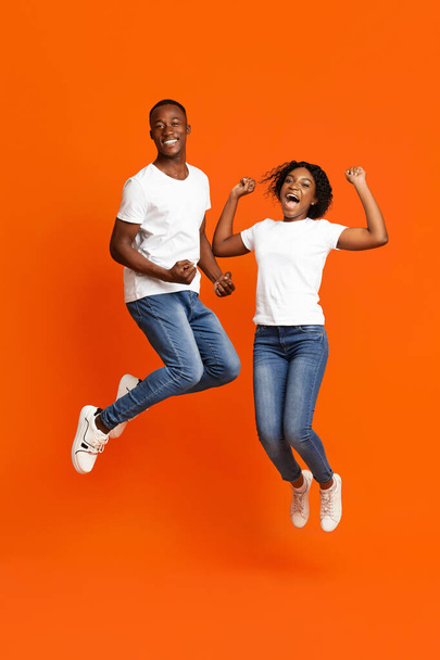 陽気なアフリカ系アメリカ人のカップルが拳を握りしめ飛び立ち - 写真・画像