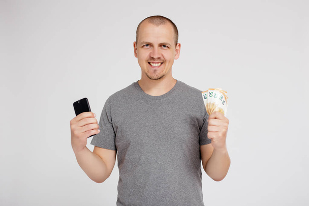 online business, cashback, online casino, sports betting and success concept - happy young man with smart phone and euro money celebrating success over grey background with copy space - Φωτογραφία, εικόνα