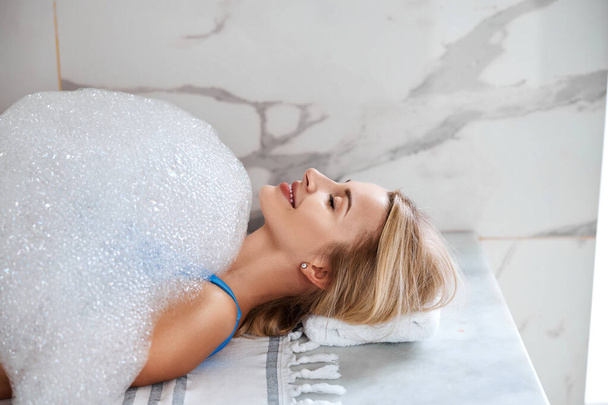 Mooie vrouw genieten spa procedure met zeepschuim in beauty center - Foto, afbeelding