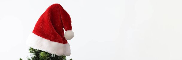 En la parte superior del árbol de Año Nuevo colgando Santa Claus sombrero rojo de cerca - Foto, Imagen